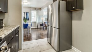 Eine moderne Küche mit dunklen Holzschränken, einem Edelstahlkühlschrank und einer Marmorarbeitsplatte.