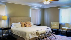 A neatly arranged hotel room with a large bed, two chairs, a bedside table, and a ceiling fan. - Spacious Luxury Home 5 min to Detroit Golf Club 4 car Free Parking (Detroit)