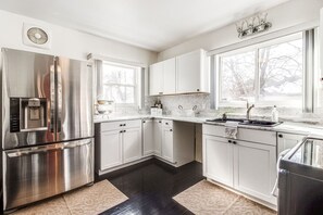 A modern kitchen with white cabinets, stainless steel appliances, and a large window providing natural light. - Spacious Luxury Home 5 min to Detroit Golf Club 4 car Free Parking (Detroit)