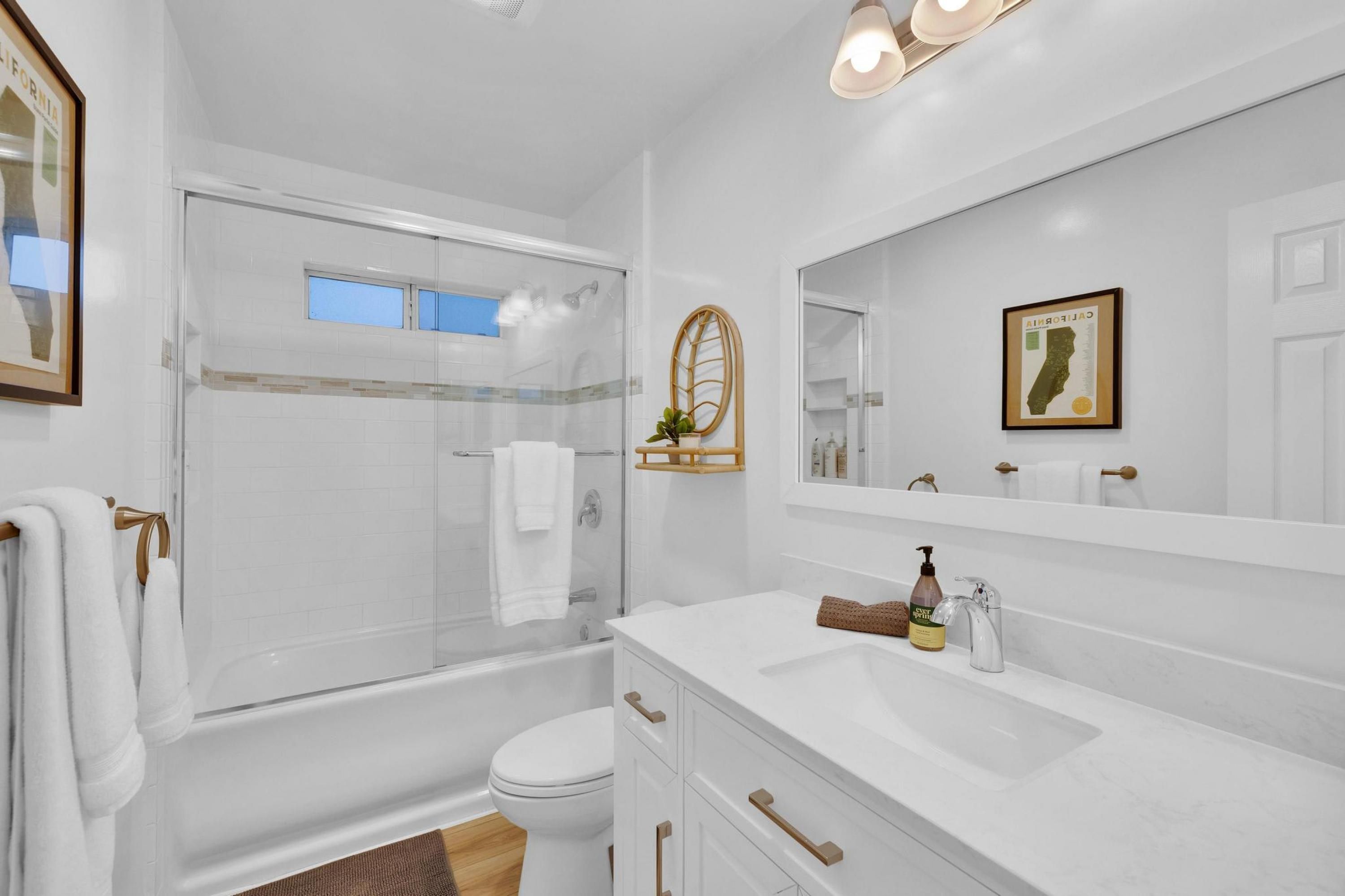 A modern bathroom with a glass shower enclosure, a white sink, and a large mirror.