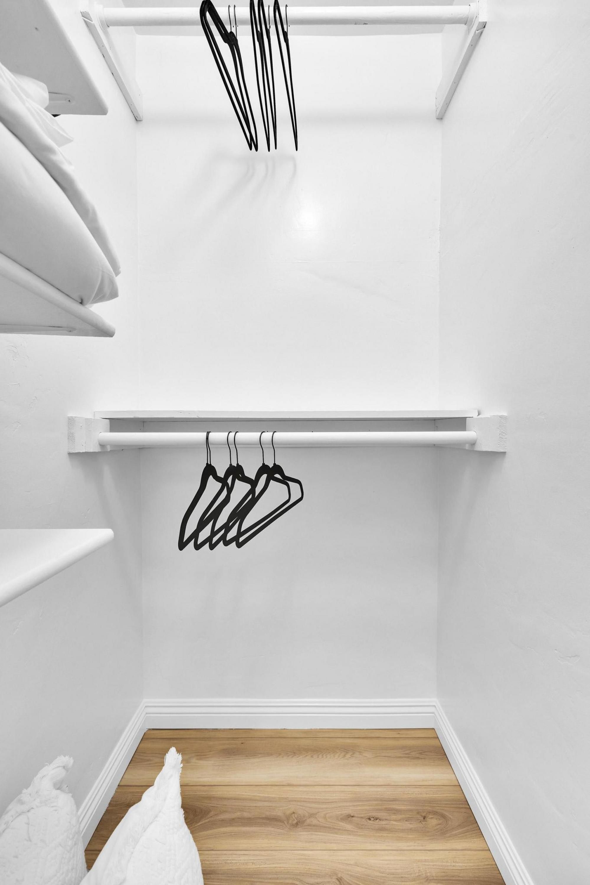 A closet with white walls, a wooden floor, and a white ceiling.