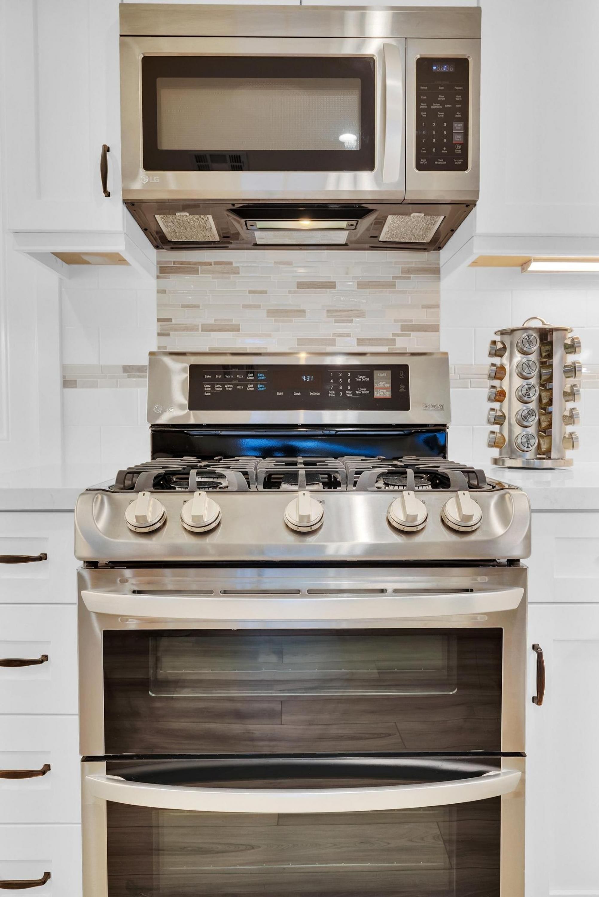 Una cocina con microondas de acero inoxidable, horno y estufa a gas.