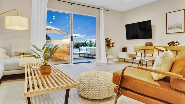 A modern living room with a sofa, coffee table, and a TV mounted on the wall. - Designer Coastal Paradise w Pool - Steps to Beach (Carlsbad)