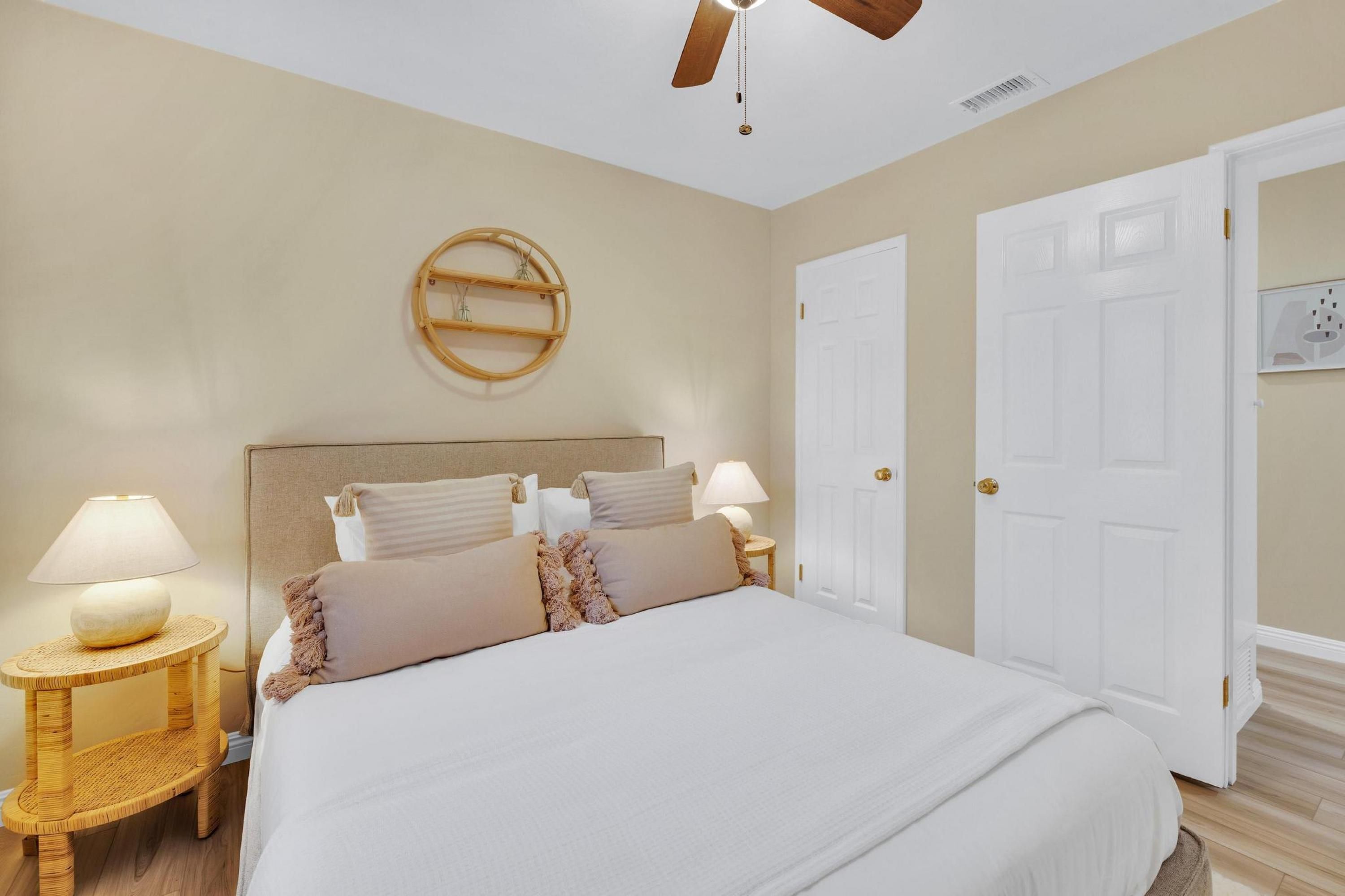 Een slaapkamer met een bed, twee nachtkastjes, een wandklok en een deur.
