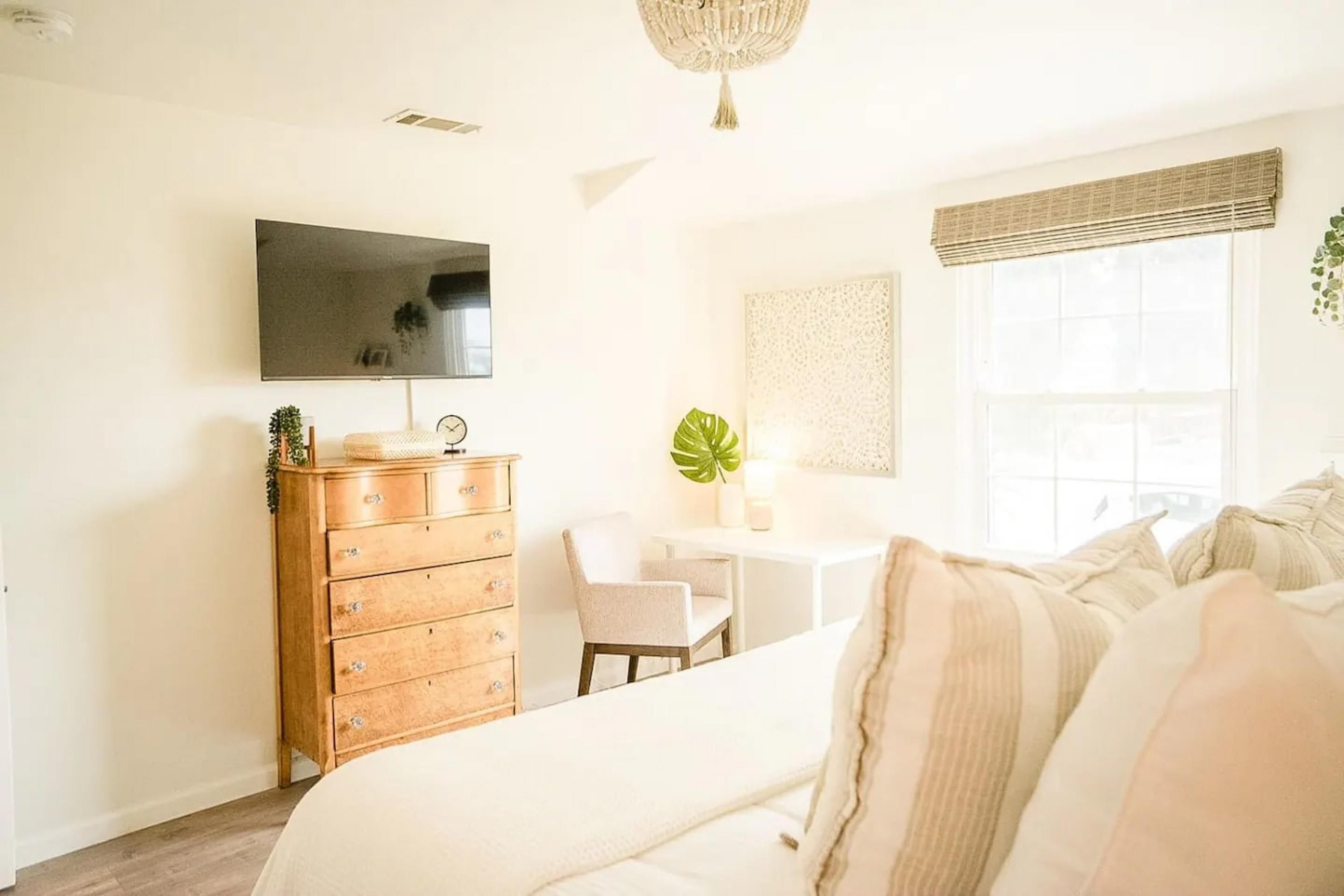 A bedroom with a bed, dresser, TV, and a window with a view.