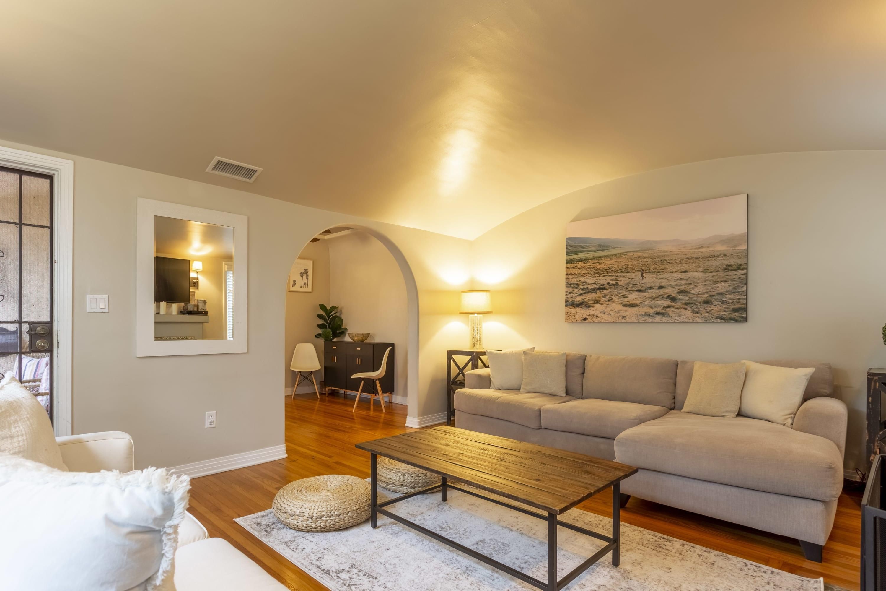 A living room with a sofa, coffee table, and a painting on the wall.