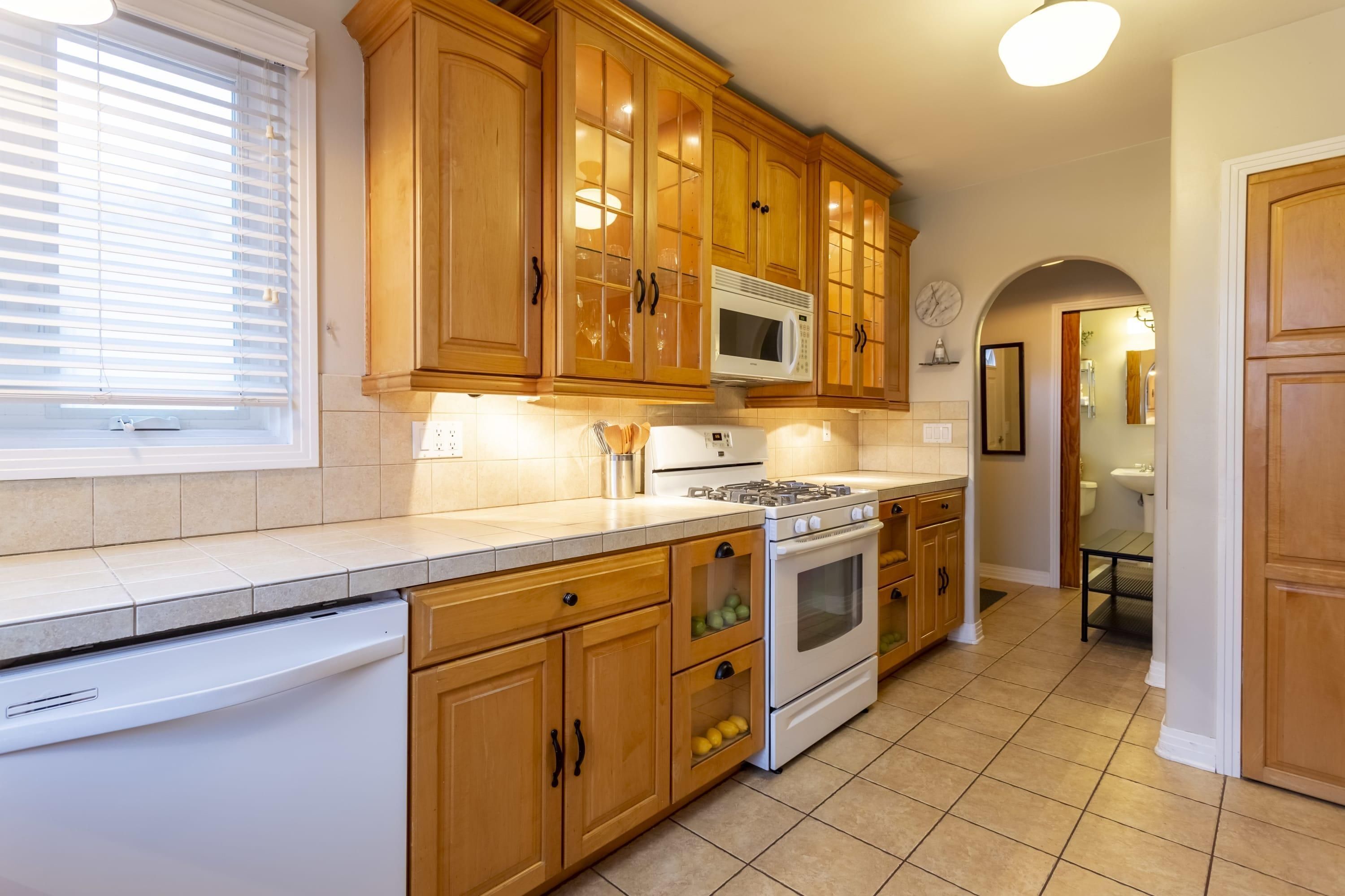 A kitchen with wooden cabinets, a microwave, stove, and dishwasher.
