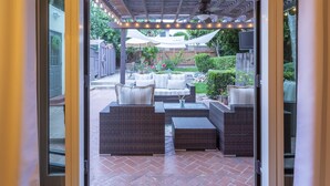 An outdoor patio with wicker furniture, a pergola with string lights, and a view of the backyard.