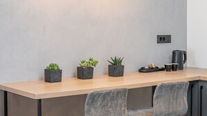 Una cocina moderna con encimera de madera, dos taburetes grises y tres macetas con plantas.