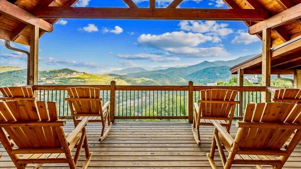 A wooden deck with chairs and a view of mountains. - Skyline Splendor Luxe Retreat With Breathtaking Views Over Downtown Gatlinburg (Gatlinburg)