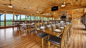 A spacious dining area with wooden tables and chairs, large windows, and ceiling fans. - Gatlinburg s Finest Majestic Views Home Theater Hot Tubs and More (Gatlinburg)