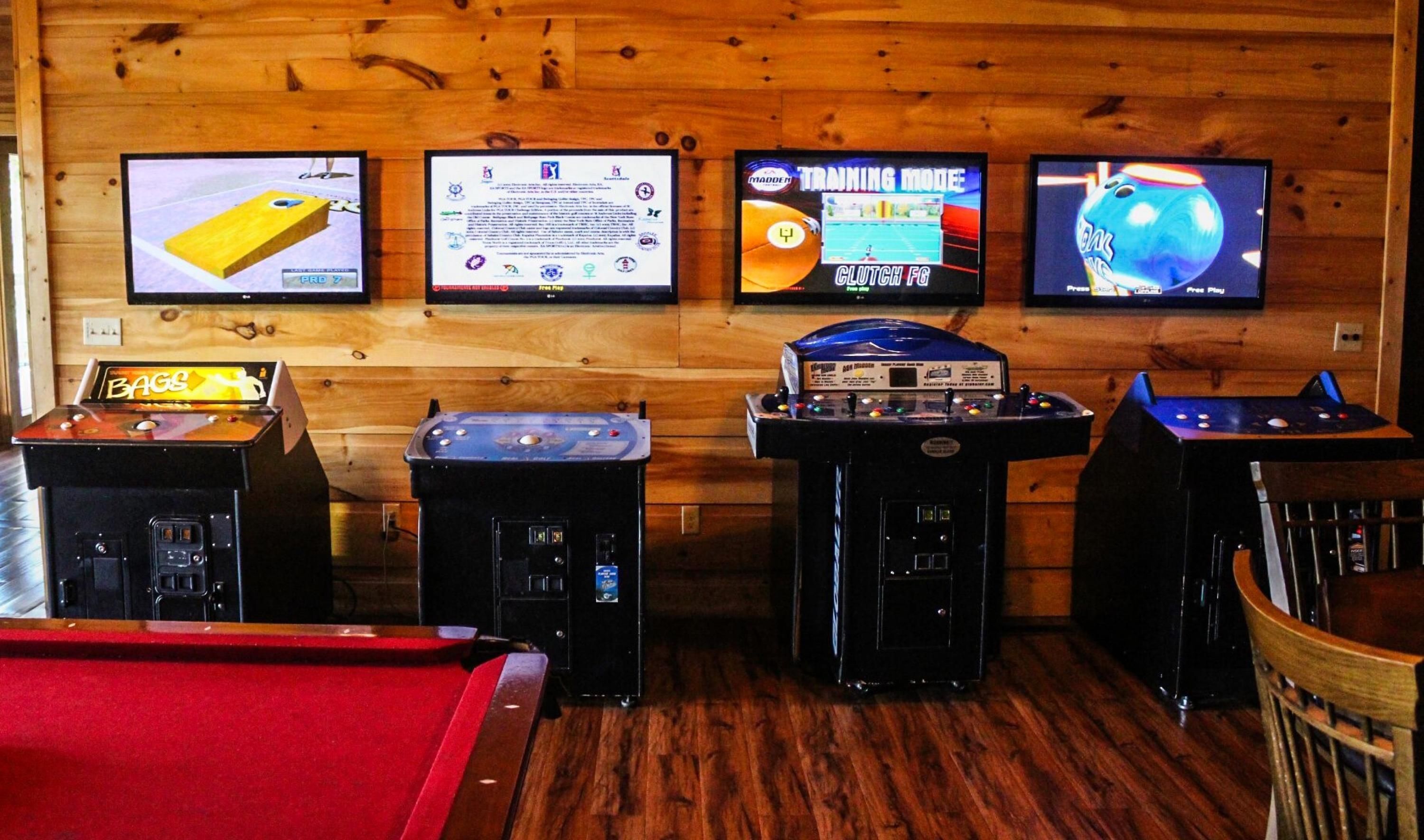 Ein Raum mit vier Spielautomaten, einem Billardtisch und Holzwänden.