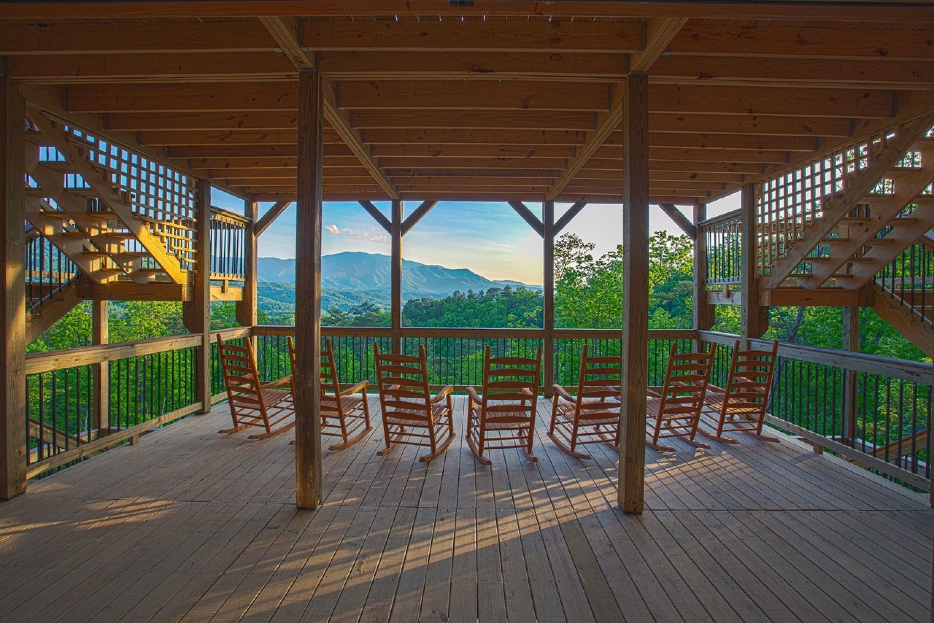 A wooden deck with a view of mountains and greenery.