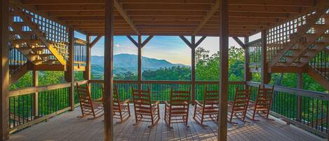 A wooden deck with a view of mountains and greenery.