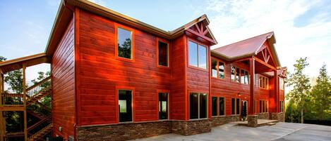 Una casa grande de madera roja con numerosas ventanas y cimientos de piedra.
