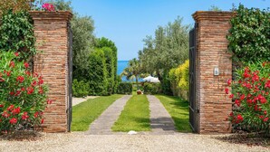 A brick entrance gate leading to a well-maintained garden with a clear view of the sea in the background. - Luxury villa with pool and direct access to the sea, Pozzillo (Pozzillo)