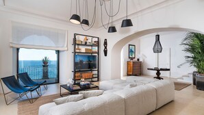 A modern living room with a large sofa, a bookshelf, and a view of the sea. - Luxury villa with pool and direct access to the sea, Pozzillo (Pozzillo)