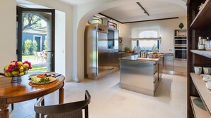 A modern kitchen with stainless steel appliances, a dining area with a wooden table, and a view of the outdoors. - Luxury villa with pool and direct access to the sea, Pozzillo (Pozzillo)