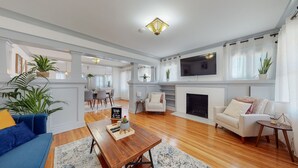A spacious living room with a fireplace, a television mounted above it, and a dining area in the background. - Cozy Alhambra 3BR Near Downtown Los Angeles (Alhambra)