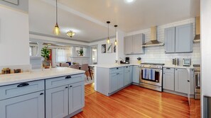 A modern kitchen with light blue cabinets, a central island, stainless steel appliances, and pendant lighting. - Cozy Alhambra 3BR Near Downtown Los Angeles (Alhambra)