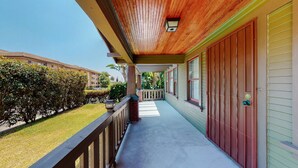 A covered porch with a wooden ceiling, a brick column, and a view of neighboring buildings. - Cozy Alhambra 3BR Near Downtown Los Angeles (Alhambra)