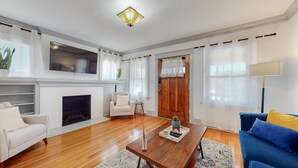 A living room with a fireplace, a sofa, a coffee table, and a television mounted on the wall. - Cozy Alhambra 3BR Near Downtown Los Angeles (Alhambra)