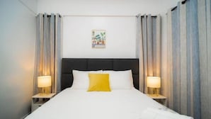 A hotel room with a large bed, two bedside lamps, a headboard, and a wall-mounted picture. - 3bd Lux City Oasis LAS Pinas (Las Pinas)