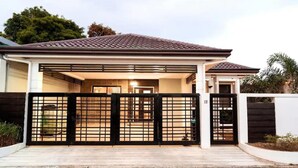 A modern house with a covered porch, a gated entrance, and a number '12' on the gate. - 3bd Lux City Oasis LAS Pinas (Las Pinas)