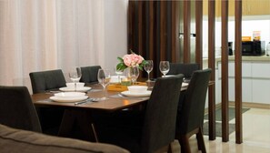Un comedor con una mesa dispuesta para cuatro personas, incluyendo platos, vasos y un jarrón con flores.