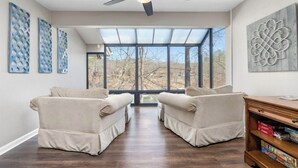A room with two beige armchairs facing a large window, a ceiling fan, and a bookshelf with board games. - Lakefront with kayaks and private dock.  Pet friendly, nearby dog park (Hot Springs Village)