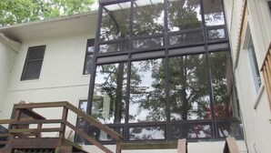 A two-story house with a large glass window wall, wooden stairs, and a white exterior. - Lakefront with kayaks and private dock.  Pet friendly, nearby dog park (Hot Springs Village)