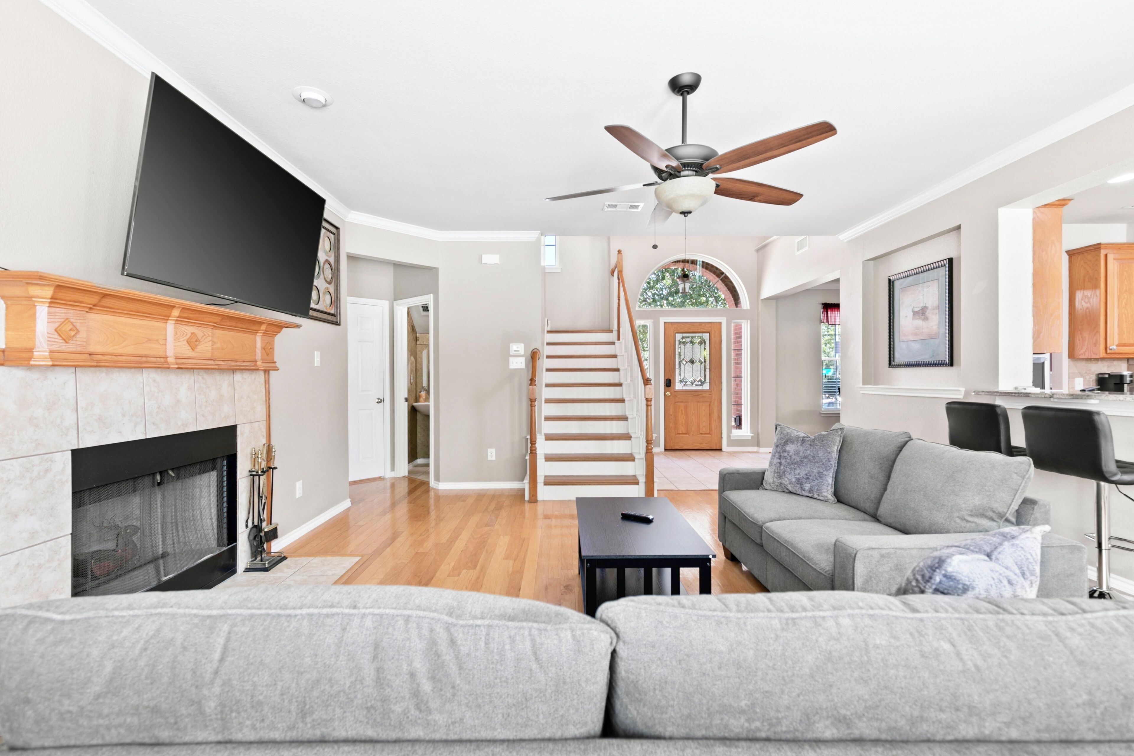 A modern living room with a fireplace, a sofa, a television, and a staircase leading to another room.