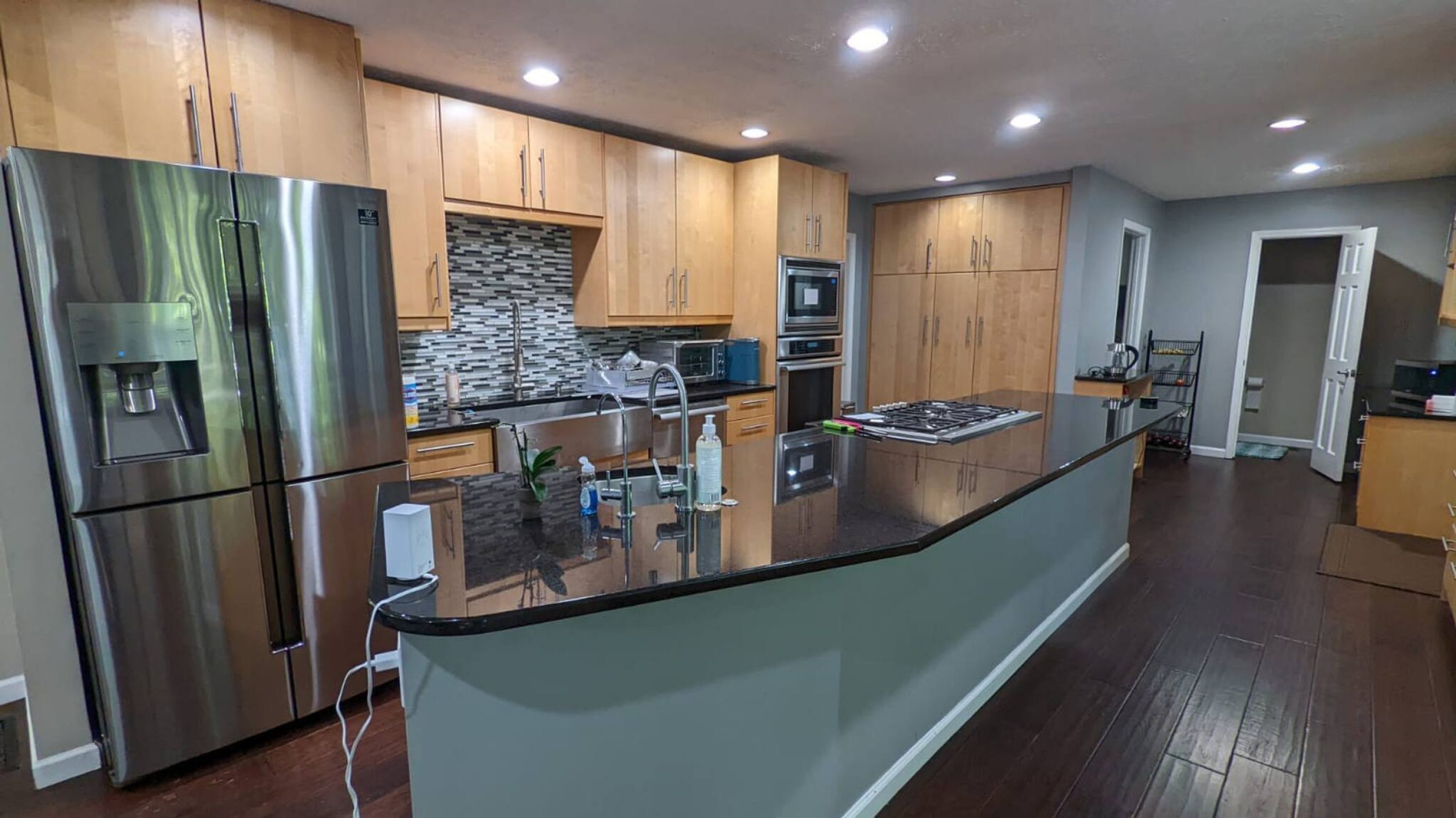 A modern kitchen with stainless steel appliances, wooden cabinets, and a central island.