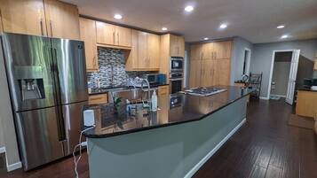 A modern kitchen with stainless steel appliances, wooden cabinets, and a central island.