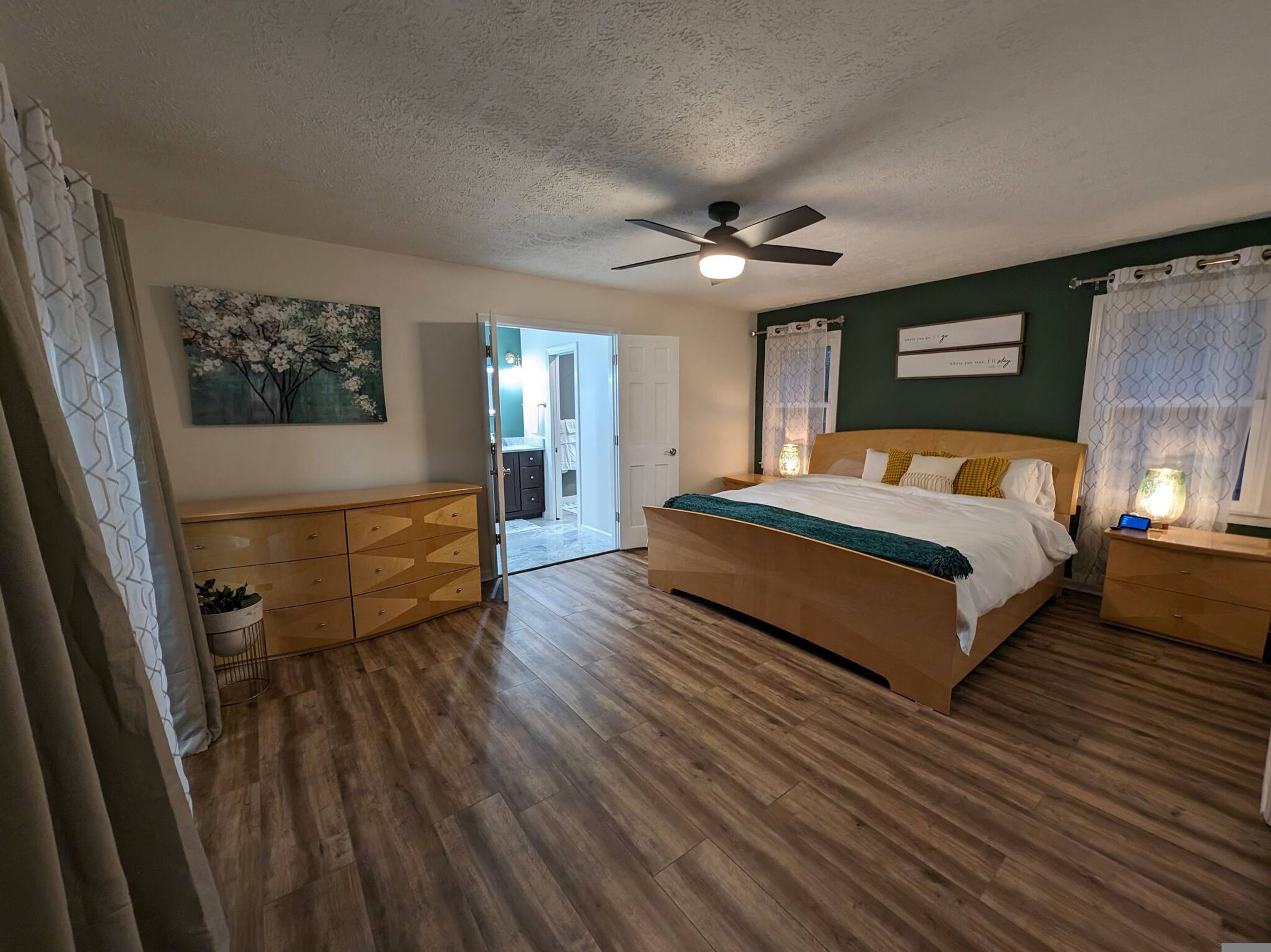 A bedroom with a wooden bed, a ceiling fan, and a nightstand with a lamp.