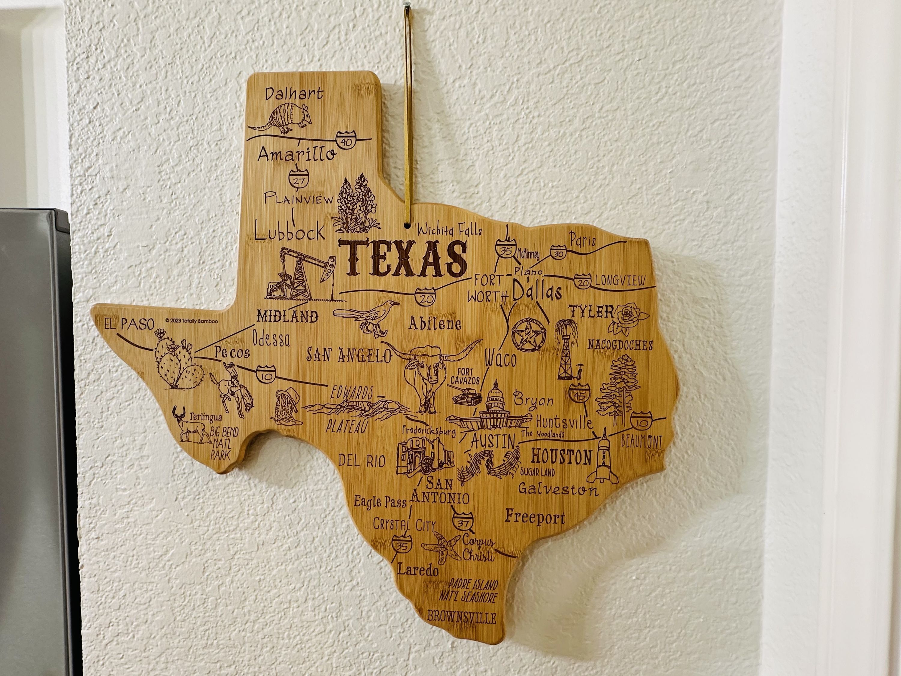 En karta över Texas, tillverkad av trä, med städernas namn och viktiga landmärken utmärkta.