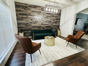 A modern living room with a green sofa, two brown armchairs, a white shag rug, and a wooden wall with a geometric pattern. - Autin - Family & Groups - Modern Lux (Round Rock)