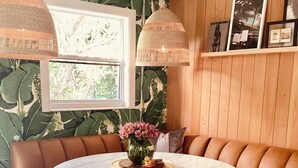 A round table with a glass top, surrounded by a brown leather sofa with metal chairs. - Charming Olde Naples Bungalow  (Naples)