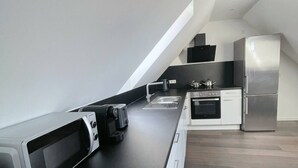 Een moderne keuken met een zwart aanrecht, roestvrijstalen apparatuur en witte kastjes.