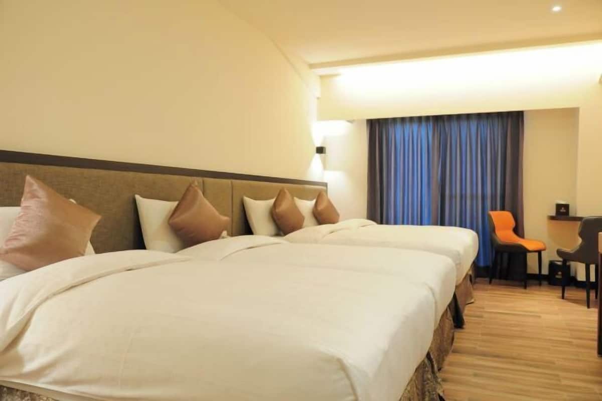 A hotel room with two beds, a desk, and a chair.