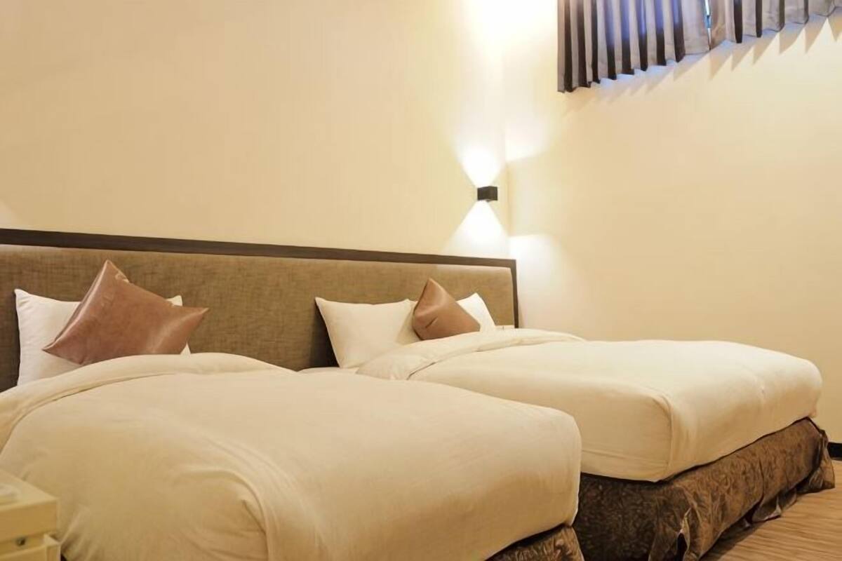 A double bed with two pillows, a bedside table, and a wall-mounted light fixture.