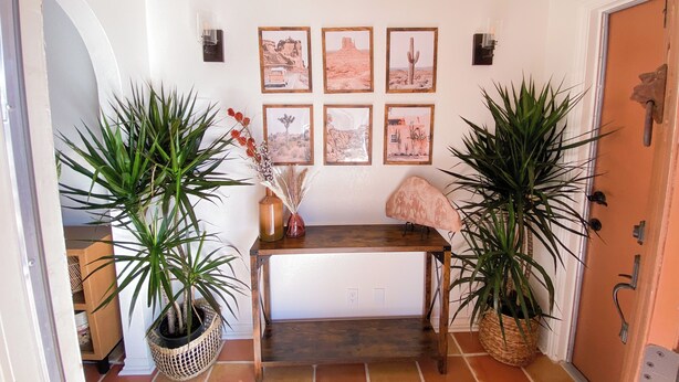 A hallway with a wooden bench, potted plants, and framed pictures on the wall. - Charming 2-bedroom house with WiFi, AC in welcoming Yucca Valley (Yucca Valley)