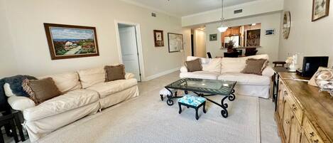 A spacious living room with a large sofa, a coffee table, and a ceiling fan.