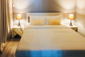 A neatly made bed with two bedside lamps, a headboard, and a pair of decorative pillows. - Angels Bed And Breakfast Sipalay City By Reddoorz (Sipalay)