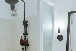 A bathroom with a shower, a toilet, and a sink. There are two bottles on the sink's shelf. - Angels Bed And Breakfast Sipalay City By Reddoorz (Sipalay)