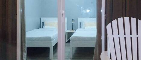 A room with two beds, a chair, and a small table.