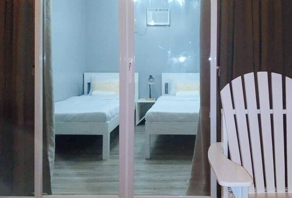A room with two beds, a chair, and a small table. - Angels Bed And Breakfast Sipalay City By Reddoorz (Sipalay)