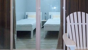 Quarto com duas camas, uma cadeira e uma pequena mesa.