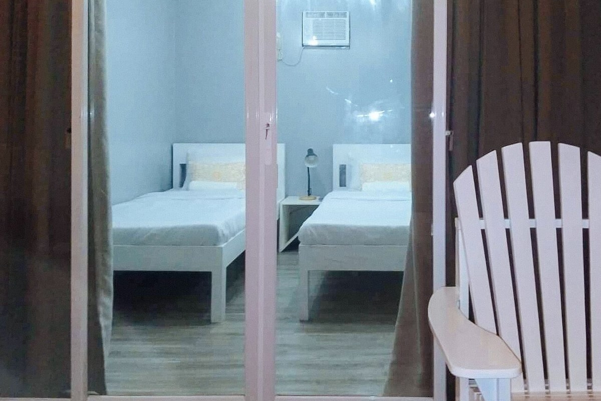 Una habitación con dos camas, una silla y una mesita.
