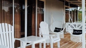 Um deck de madeira com mobiliário branco, incluindo cadeiras e uma mesa.